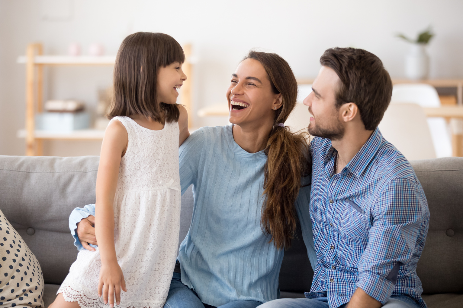 Kid daughter having fun talking to happy parents laughing together